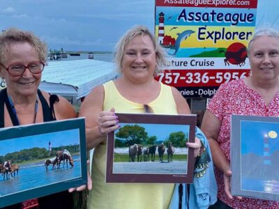 Assateague Explorer cruise visitors holding an art print of Assateague wild ponies