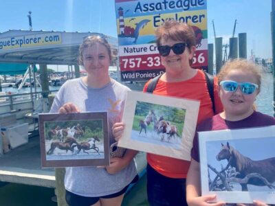Assateague Explorer cruise visitors holding an art print of Assateague wild ponies